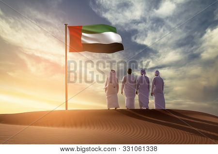 Emirati Young Men Standing On Sand Dune On The Desert Looking In  Uae Flag Celebrating National Day 
