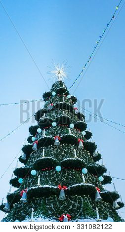 Christmas Tree Against Blue Sky. Vertical Photo. Christmas And New Year Holiday Concept
