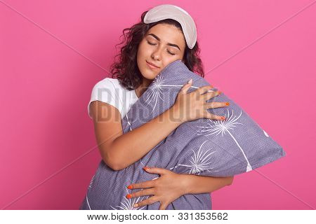 Horizontal Shot Of Pretty Young Caucasian Woman Embraces Gray Soft Pillow, Keeps Eyes Closed And Wan