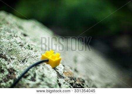 Yellow Generic Building Toy Block Wired With Xlr Cable, Sitting A Rock, Outside