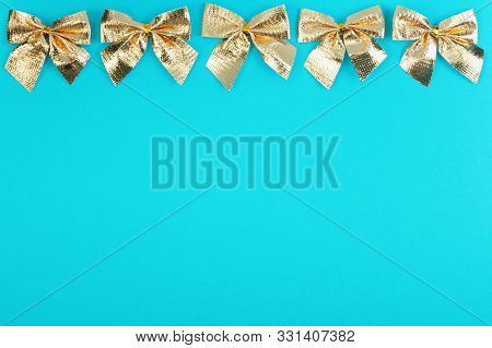 Gold Christmas Bows On Blue Background. Holidays Mock-up With Copy Space For Your Design. Flat Layou
