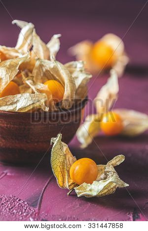 Fresh Juicy Group Organic Cape Gooseberry In Clay Dish On Dark Claret Bordeaux Concrete Surface. Phy