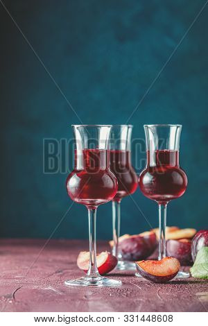 Plums Strong Alcoholic Drink In Grappas Wineglass With Dew. Hard Liquor, Slivovica, Plum Brandy Or P