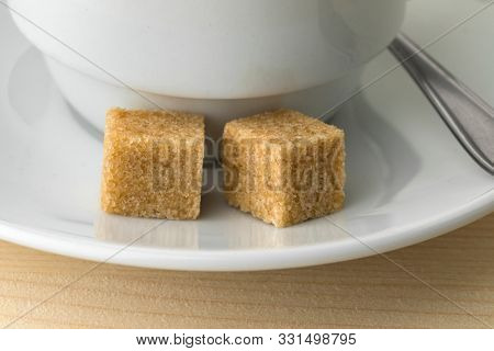 Cup of coffee with two fairtrade cane sugar cubes close up