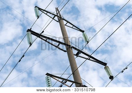 Supports High-voltage Power Lines Against The Blue Sky With Clouds. Electrical Industry