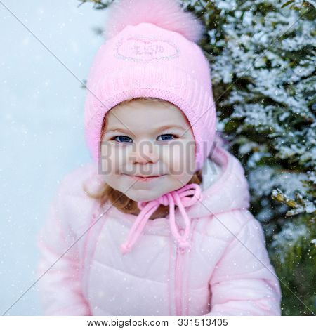 Portrait Of Little Toddler Girl Walking Outdoors In Winter. Cute Toddler Eating Sweet Lollypop Candy