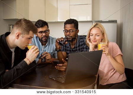 Group Of Young People Sitting At Table Using Laptop