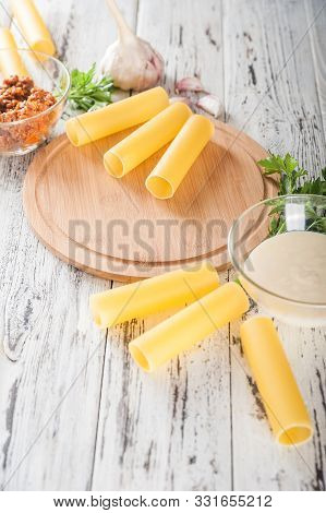 Cannelloni On A Plate With Meat And Tomato Sauce. Italian Paste. Crude Cannelloni On A Kitchen Table