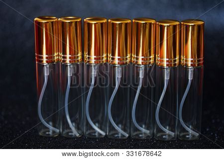Seven Transparent High Perfume Atomizers On A Dark Shiny Background. Perfumes And Fragrances. Bokeh 