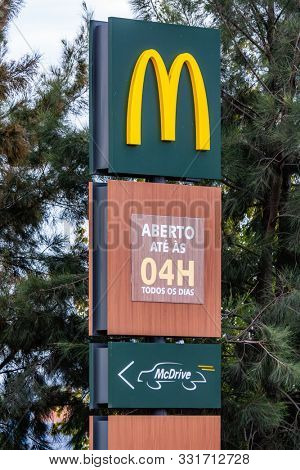 Coina, Portugal - October 23, 2019: Signboard of McDonaldâs with Golden Arches at the entrance of a McDonalds restaurant informing of the McDrive drive thru service and serving hours