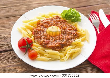 Penne Pasta With A Bolognese Tomato Beef Sauce On Wooden Table