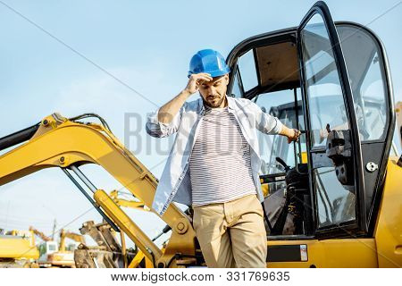 Handsome Builder Or Construction Worker Getting Out Of The Escavator On The Construction Site