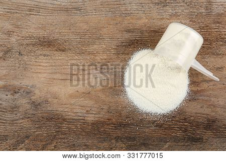Overturned Measuring Scoop With Protein Powder On Wooden Table, Top View. Space For Text