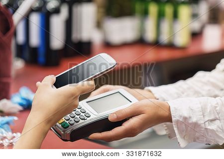 The Buyer Pays For The Item At The Cash Register Using A Smartphone. Contactless Payment Process In 