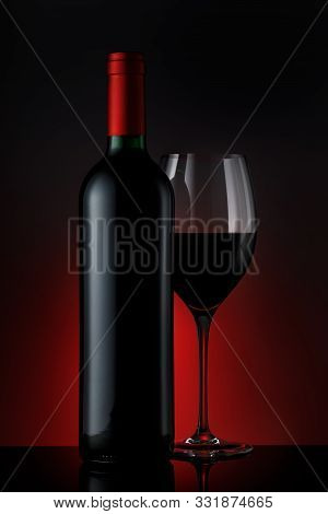 Bottle Of Red Wine With A Glass On A Black Background, Vertical Close-up Image