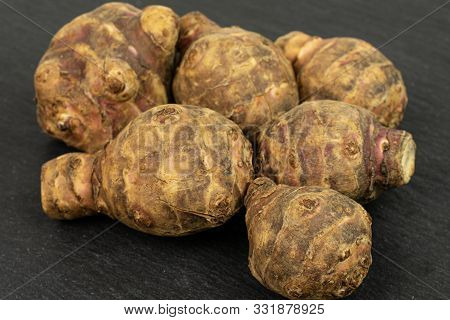 Group Of Six Whole Fresh Brown Jerusalem Artichoke On Grey Stone
