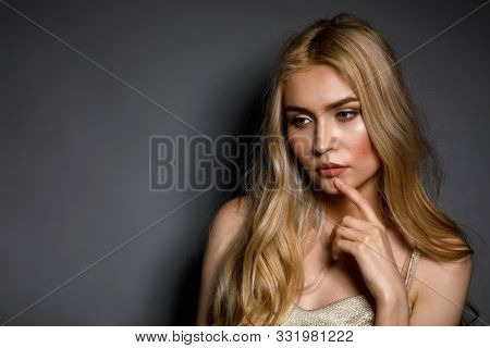 Pensive Young Beautiful Girl On Gray Background With Copy Space