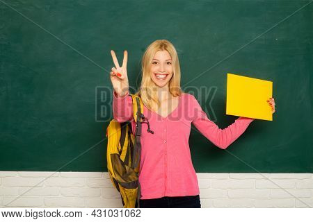 Female Teacher In The Classroom On The Chalkboard. College Girl In Class. Student Girl Holding Empty