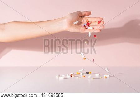 Various Colorful Pills Dropped From Top. Medicines Jumped On Table. Pink Background. Selective Focus