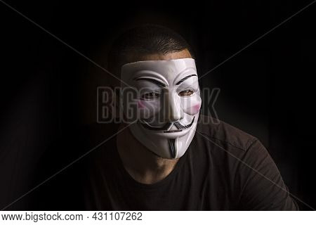 Ukraine, Odessa, Summer 2021/ Unidentified Man Wearing A Guy Fawkes Mask In A Dark Room.