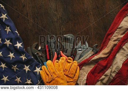 Worn work gloves on tools with US American flag. Made in USA, American workforce, blue collar worker, or Labor Day concept.