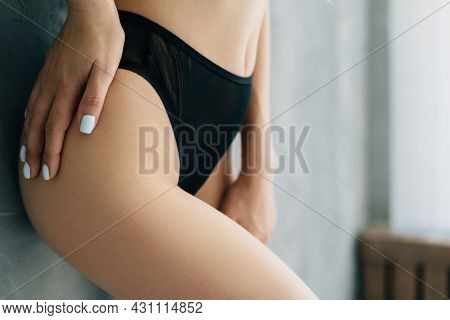 Beautiful Female Ass And Thigh In Black Panties Close-up. The Girl Touches Her Side With Her Hand. A