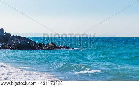 A Landscape Of A Turquoise Sea With Waves Against A Bright Sky And Blue Rocks Can Be Used As A Backg