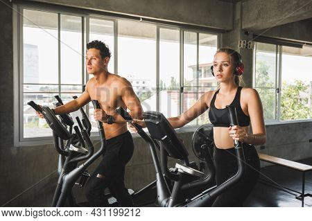 Group Of People At The Gym Exercising On The Cross Trainer Machine. Young Fitness Men And Women Doin
