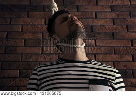Depressed Man With Rope Noose On Neck Near Brick Wall, Low Angle View