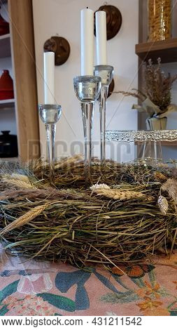 A Wreath Of Dry Herbs In A Composition With Candles On The Table