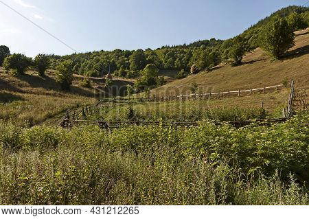 View Of A Mountain Pasture With Traditional Hayrick For The Winter, Forest And A Vegetable Garden Ne