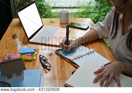 Closed Up With Office Desk And Businesswoman Writing On Notebook And Empty Screen Of Laptop Place On