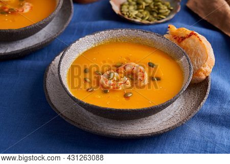 Vegetarian Healthy Autumn Pumpkin And Carrot Cream Puree Soup With Shrimps, Herbs And Ciabatta Toast