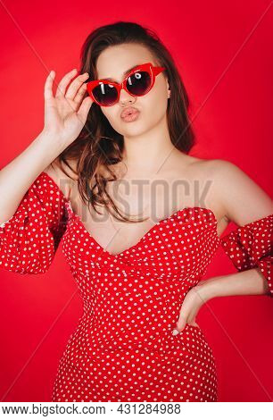 Stylish Attractive Young Woman Posing In Red Polka Dot Tight-fitting Dress And In Cat Eye Glasses, S