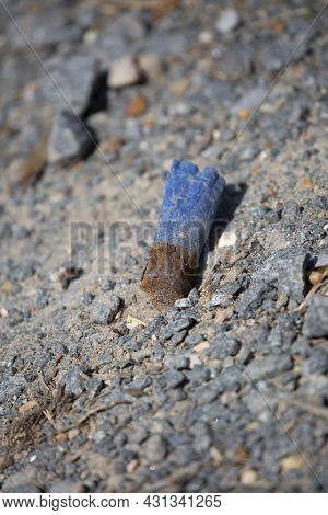 Rusty, Discharged Blue Ammunition Shell On The Gravel Ground
