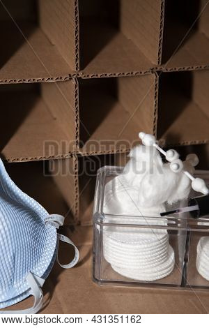 Two Blue N-95 Masks And A Plastic Box Of Makeup Rounds, Cotton Balls, And Cotton Swabs In Front Of A