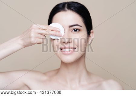 Beautiful Caucasian Woman Gently Cleaning Face With Makeup Remover Pad On Beige Background