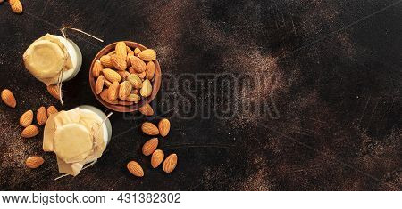 Plant Based Almod Milk In Bottles On Brown Background. Copy Space. Top View