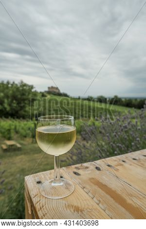 Glass Of White Wine On The Terrace Close-up Across Vineyards, Castle. And Blue Sky. Travel, Winemaki