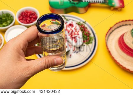 Woman Hand Holding A Tequila Glass And Chile En Nogada, Ingredients, Toy Guitar And Little Hat Out O