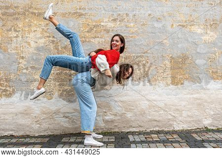 Funny Teenager Carrying Her Best Friend Piggyback On The Pavement At The Old Wall, Positive Emotions