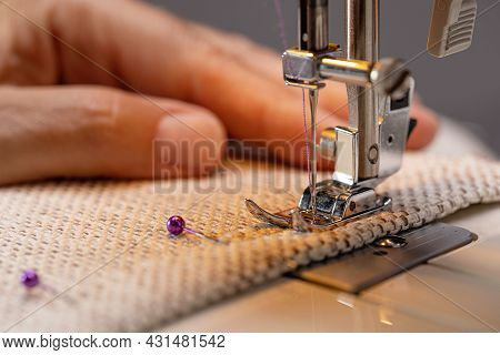 Sewing Machine Foot On Fabric With Needle And Thread Ready To Sew. The Operator's Hand On The Materi