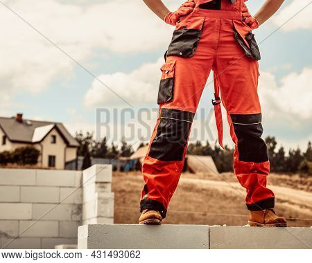 Low Section Legs Of Construction Worker Wearing Workwear Trousers And Brown Leather Work Boots Stand