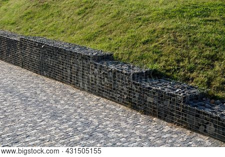 Gabion Granite Wall. Wire Baskets Filled With Stones. On The Edge Of The Sidewalk, In The Bend Of Th