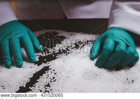 Man Hands Wearing Gloves Hold Polymer Pallet. Plastic Beads On Green Gloved Hand. Polymer Beads. The