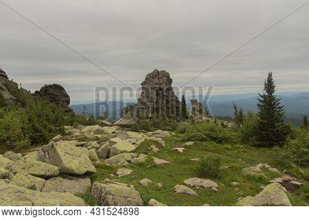 Large Kurum Stones Lie In The Forest In The Mountains, Stones Covered With Moss, Against The Backgro