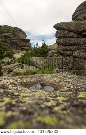 Large Kurum Stones Lie In The Forest In The Mountains, Stones Covered With Moss, Against The Backgro