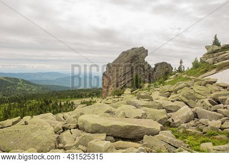 Large Kurum Stones Lie In The Forest In The Mountains, Stones Covered With Moss, Against The Backgro