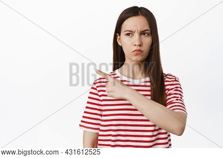 Girl Squinting, Pointing And Looking Left With Doubtful Uspet Face, Express Disbelief, Standing In T