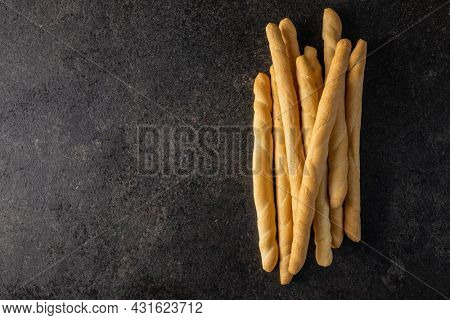 Grissini sticks. Traditional italian bread sticks on black table. Top view.